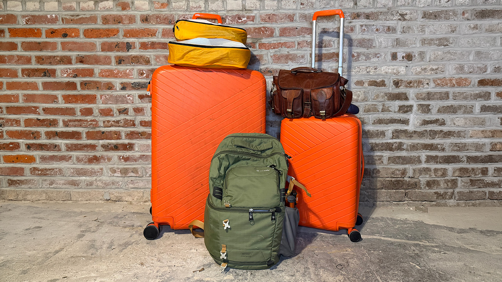 luggage My neon orange OOO luggage set, along with my leather crossbody bag, my SLR backpack, and two orange packing cubes.