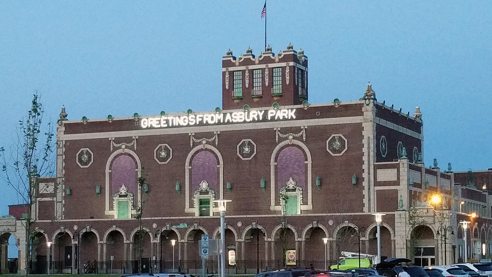 The Asbury Park Convention Hall, the illuminated sign on the building says "Greetings From Asbury Park"