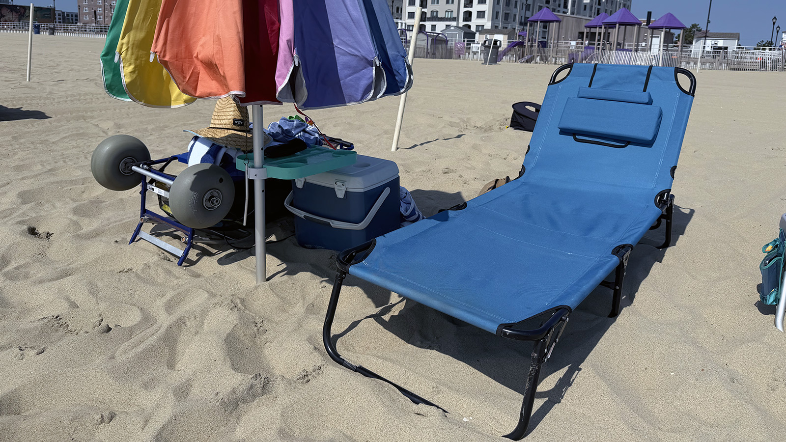 chaise-lounge Blue adjustable beach chaise lounge set beneath a rainbow umbrella on the sand in Asbury Park.