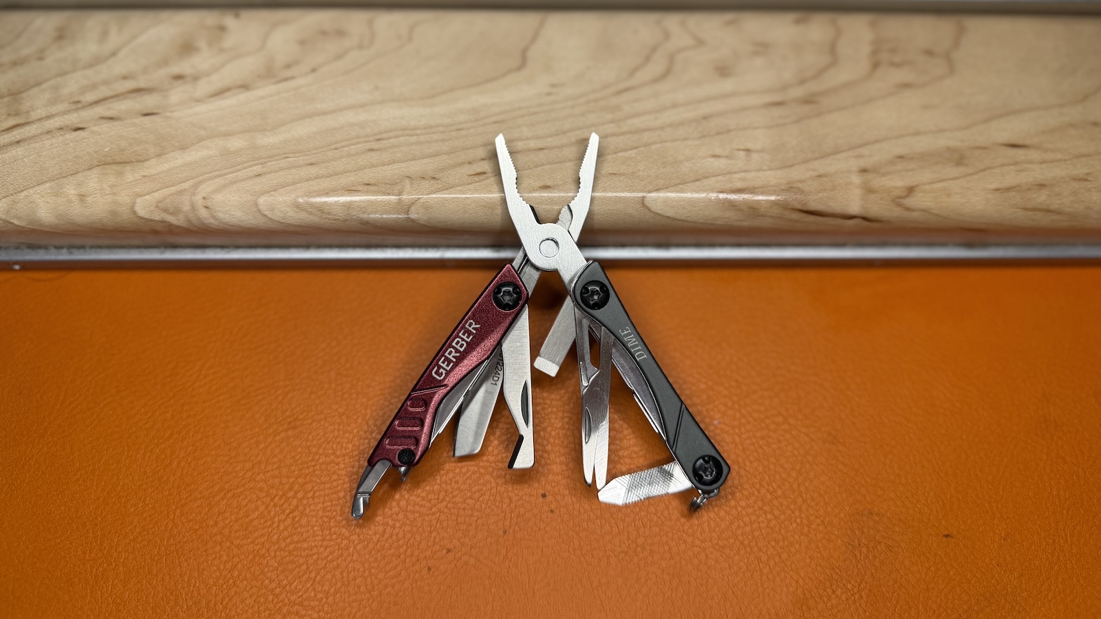 gerber-dime The Gerber Dime multi-tool is lying on an orange leather background and a pale wood keyboard rest.