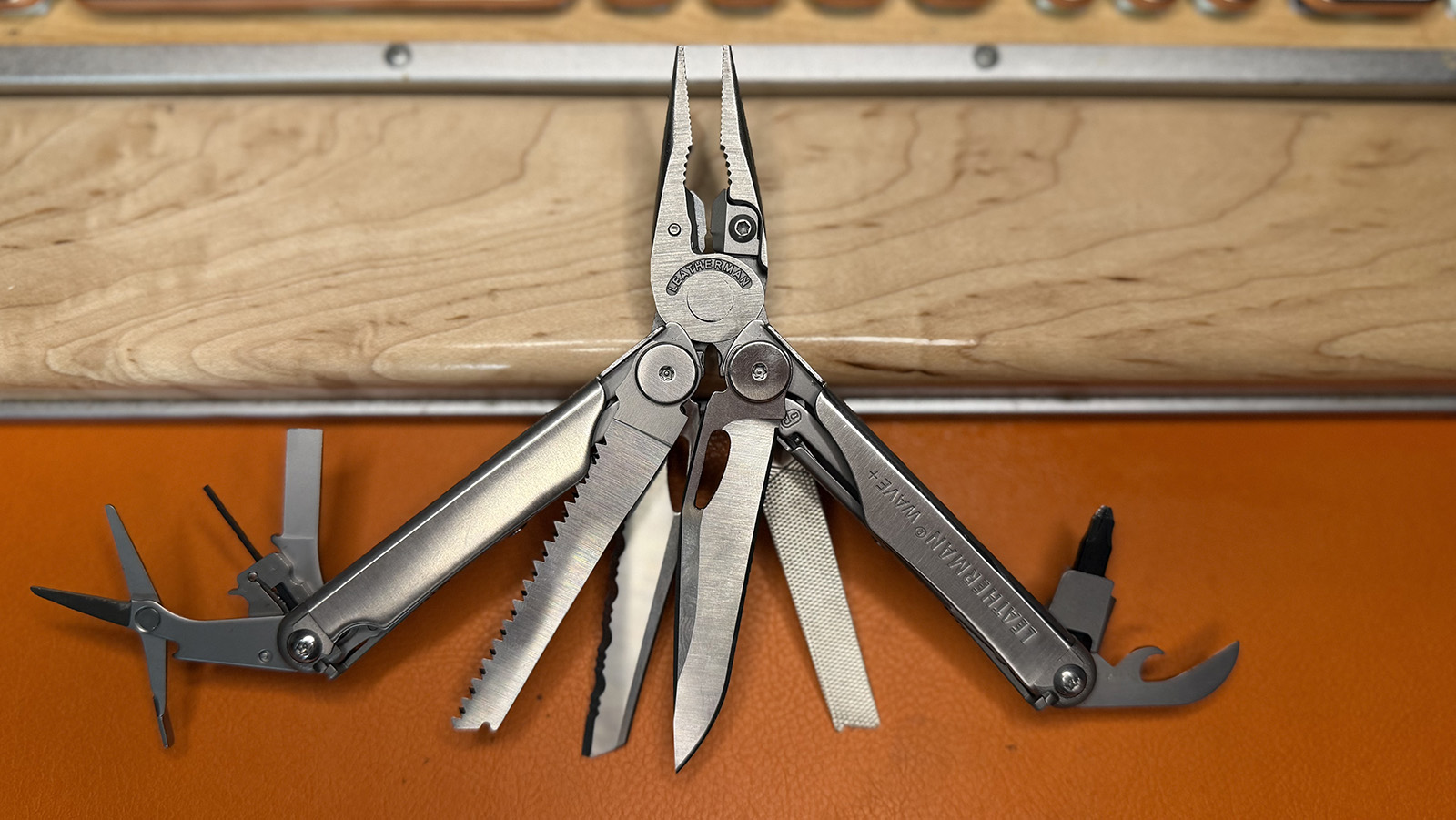 leatherman-wave-plus The Leatherman Wave Plus multi-tool is lying on an orange leather background and a pale wood keyboard rest.