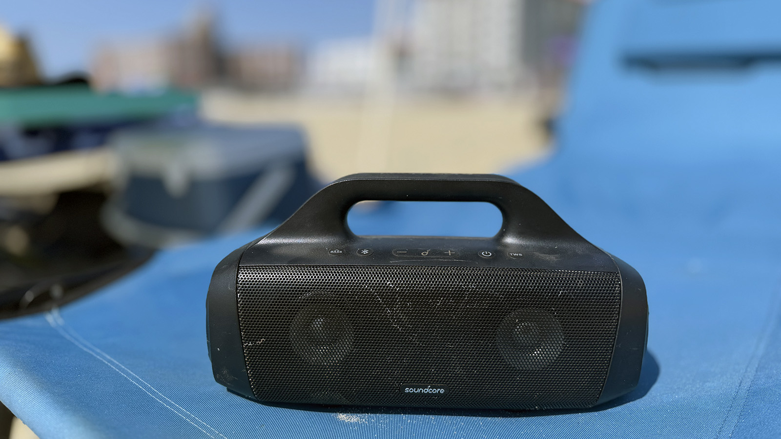 motion-boom Black Soundcore Motion Boom portable speaker resting on a blue beach chair.