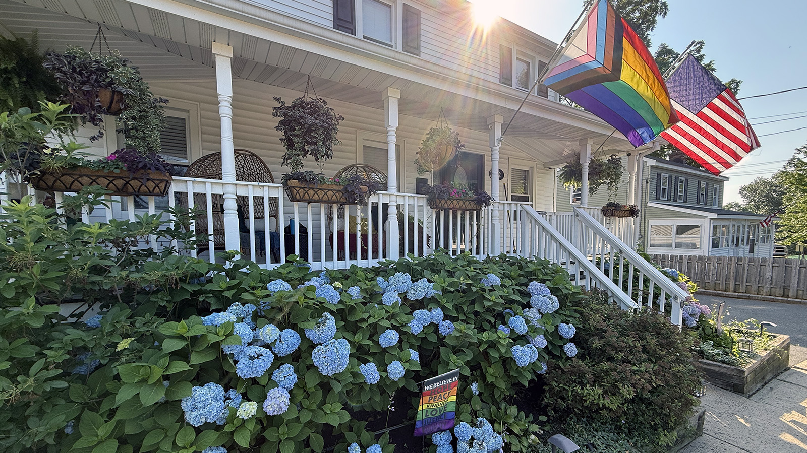 porch-tile My front porch surrounded by blue hydrangeas, hanging baskets, wicker chairs, and Pride and American flags.