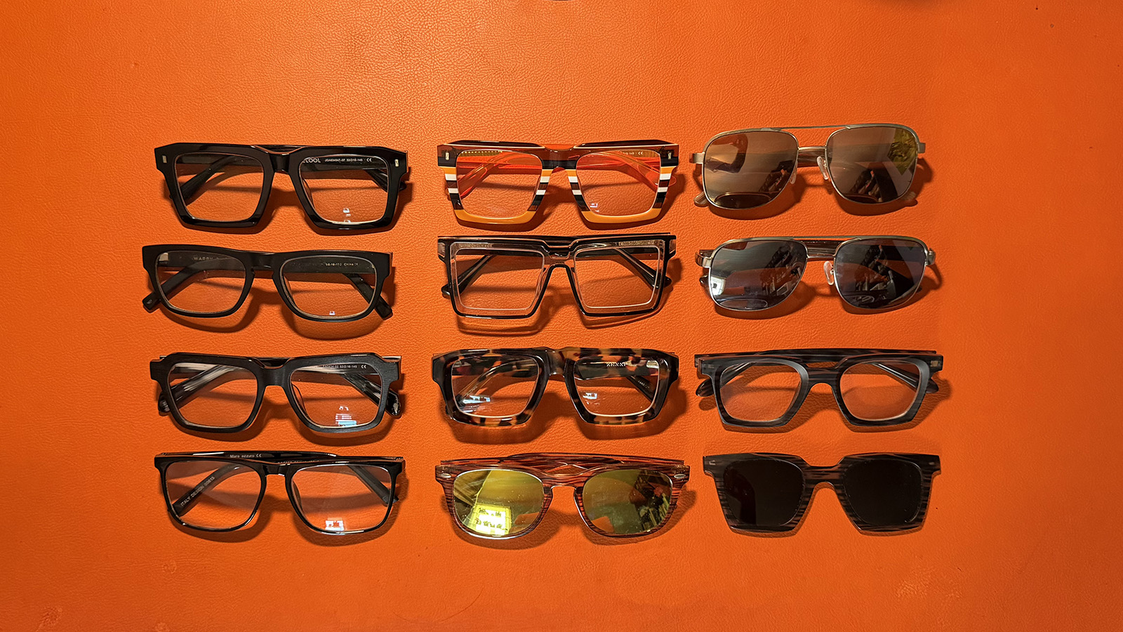 glasses A array of prescription glasses and sunglasses in various shapes and colors on an orange leather mat.