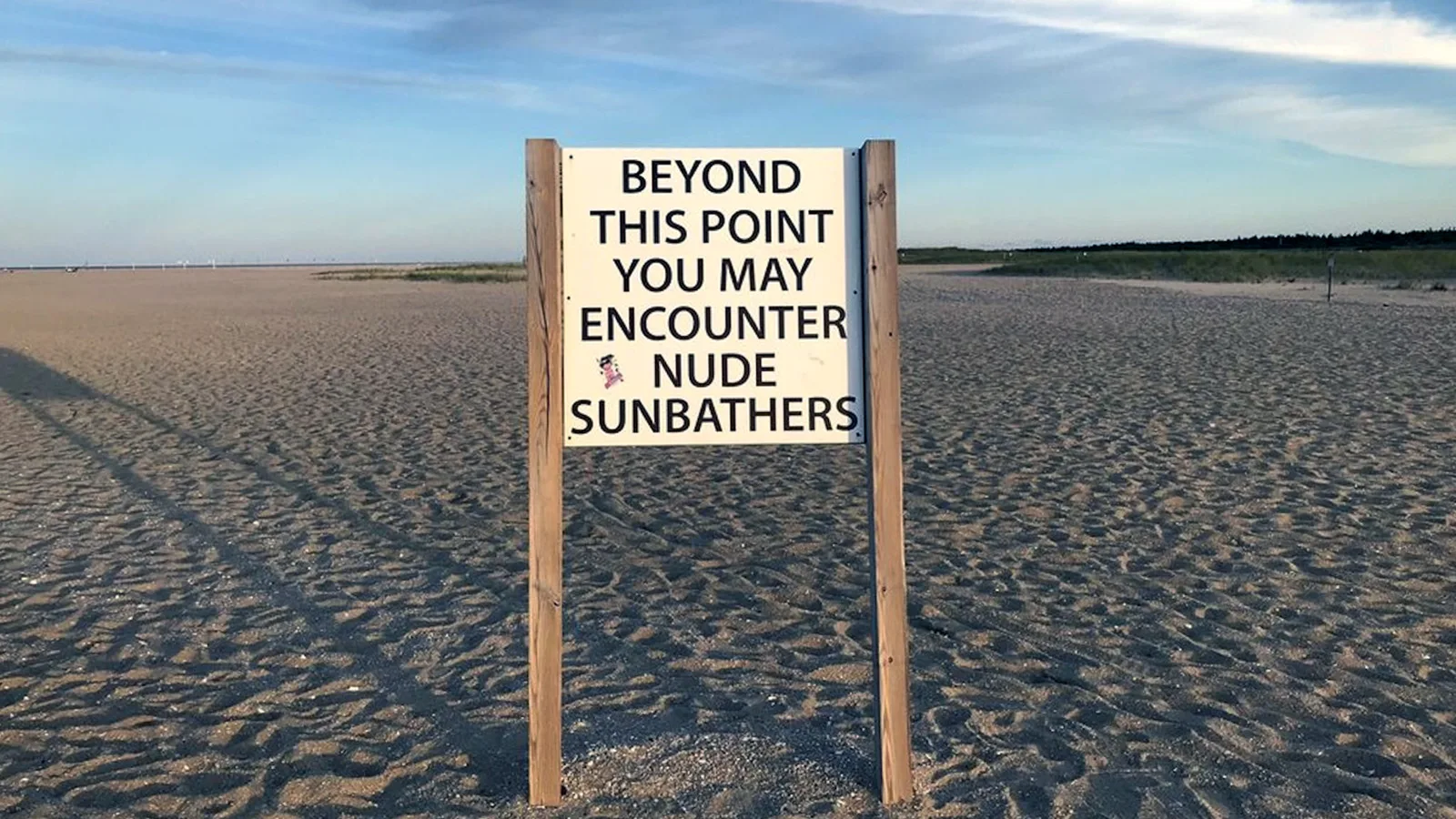 A warning sign at the entrance of Gunnison Beach reads: "Beyond this point you may encounter nude sunbathers."