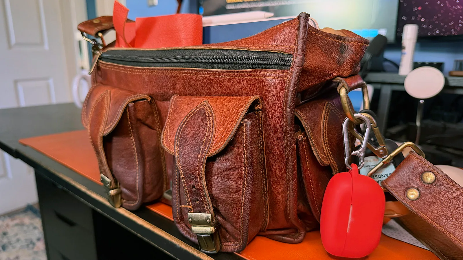 upgraded-hardware Close-up of the leather travel bag showing the replacement brass D-ring, swivel clasp, push-button clasps, and customized shoulder strap hardware.