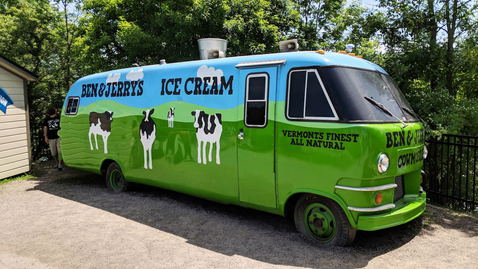 A vintage Ben & Jerry’s ice cream bus painted bright green and blue with cows along the side.